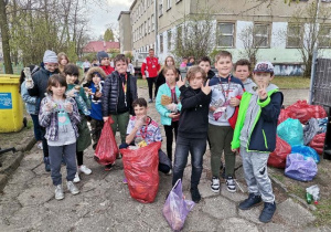 Uczniowie prezentują worki z zebranymi podczas akcji śmieciami.